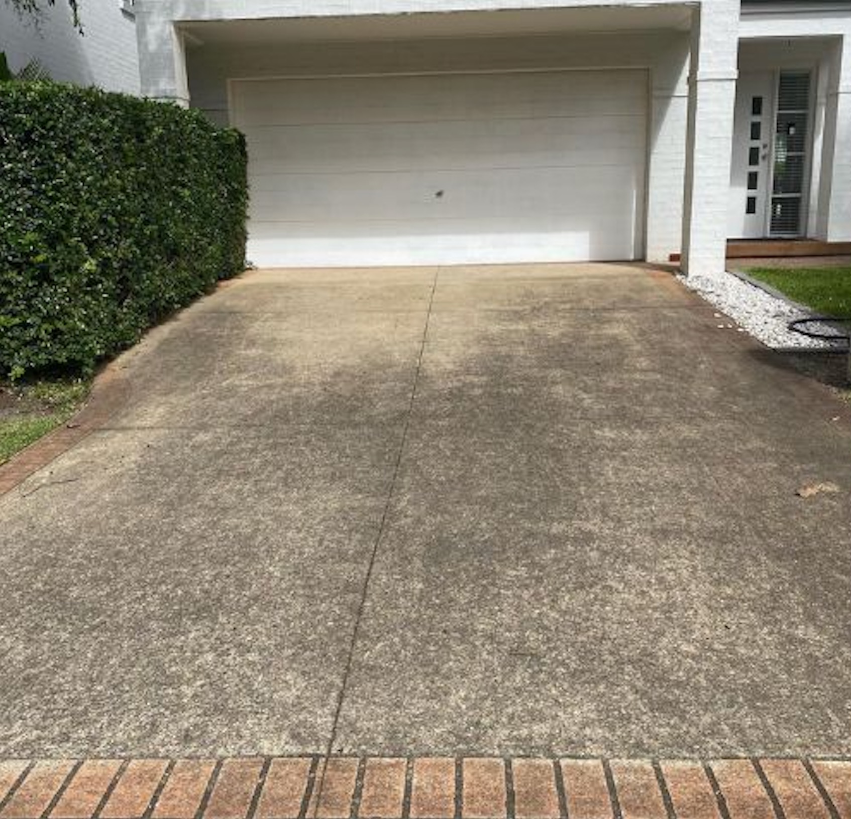Before: Dirty driveway with brick border before and after power washing